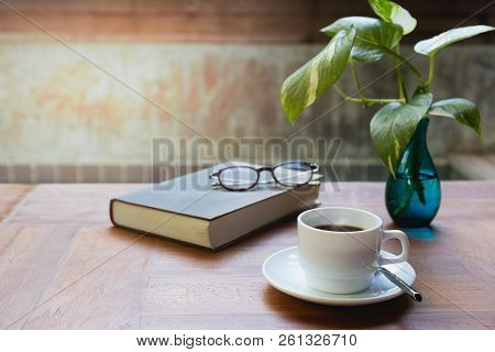 Cup Of Coffee And Glasses On Top Of Readbook On Wood Table