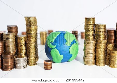 A Lot Of Coins On White Table With Earth Model. Abstract Photo Of Money