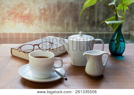 Cup Of Coffee And Glasses On Top Of Readbook On Wood Table.