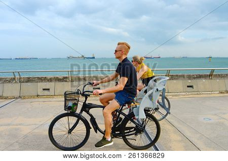 Singapore - February 6, 2017: Couple Riding Bycicles At Singapore Harbor. Singapore Is Major Financi