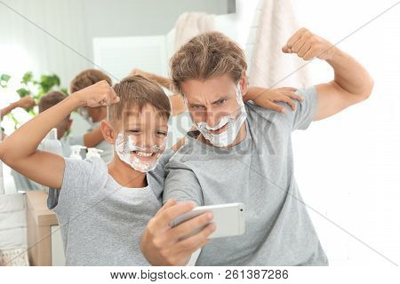 Father And Son Taking Selfie With Shaving Foam On Faces In Bathroom