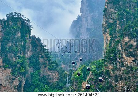 Famous tourist attraction of China - Zhangjiajie stone pillars cliff mountains in fog clouds with cable railway car lift at Wulingyuan, Hunan, China. With camera pan