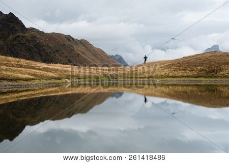 Mountain lake with a mirror reflection of clouds. View of Main Caucasian ridge. Tourist enjoys the picturesque scenery. Koruldi, Samegrelo-zemo svaneti, Georgia