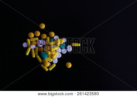 Color Capsules. Medicine Pills On Black Background Top View Copy Space