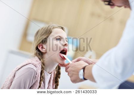 Little girl in clinic having a checkup with laryngologist