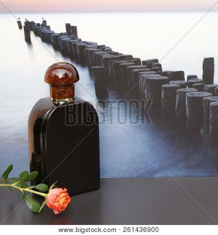 Eau De Toilette, Large Perfume Bottle In Front Of The Picture Of A Groyne In The Sea Decorated With 