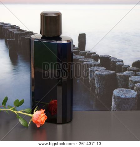 Eau De Toilette, Large Perfume Bottle In Front Of The Picture Of A Groyne In The Sea Decorated With 