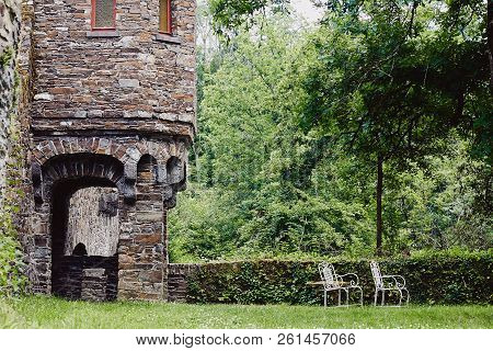 Two Vintage White Chairs Outdoor In Green Courtyard Of Medieval Castle