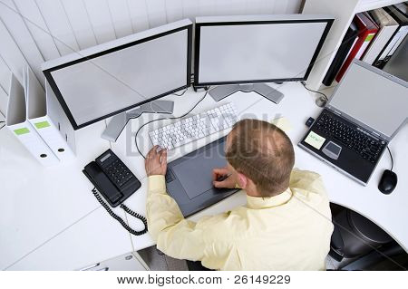 Grafik-Designer bei der Arbeit hinter zwei große Flachbildschirme und einen Laptop einen Freistellungspfad von scr