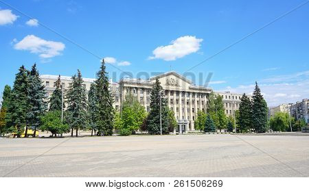 Empty Square With Green Trees Near Building. Modern Building With Blue Sky And Clouds