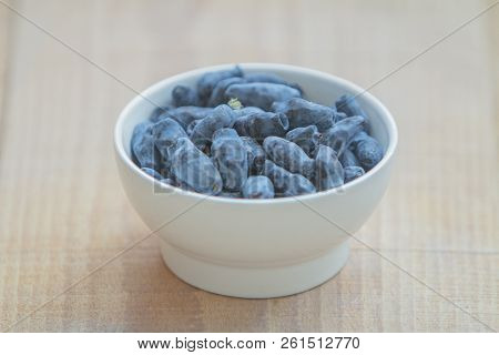 Honeysuckle Blue Berry (honeyberries, Woodbine, Woodbind) On White Plate On Wooden Table