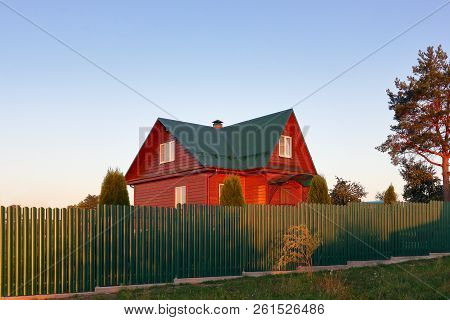 Wooden House Under Green Metal Roof House Behind The Green Fence Sunset Lihgts Photo