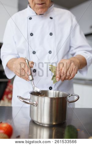 The Aged Chef Cooking A Soup In The Kitchen. The Concepy Of Cooking