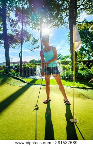 Mini Golf - Woman playing Golf on green grass at sunset