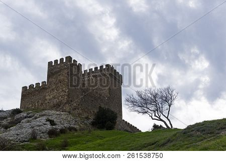 Genoese Fortress In Sudak, Crimea. Consular Castle And A Lonely Tree Against A Cloudy Sky. Early Apr