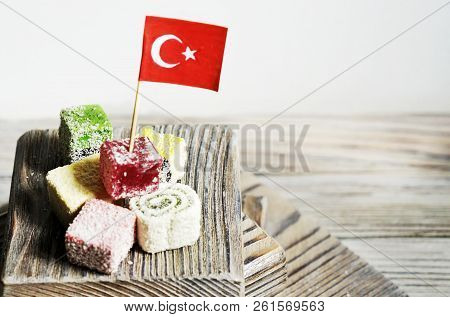 Various National Oriental Sweets, With Paper Flags Of Turkey, Turkish Delight On A Wooden White Brus