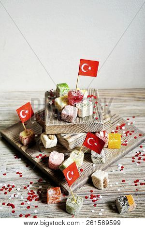Various National Oriental Sweets, With Paper Flags Of Turkey, Turkish Delight On A Wooden White Brus