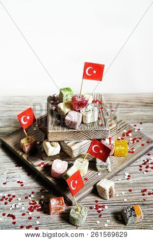 Various National Oriental Sweets, With Paper Flags Of Turkey, Turkish Delight On A Wooden White Brus