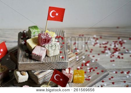 Various National Oriental Sweets, With Paper Flags Of Turkey, Turkish Delight On A Wooden White Brus