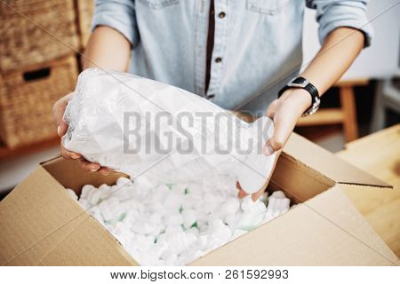 Hands Of Woman Putting Fragile Vase In Box Filled With Foam Pettels
