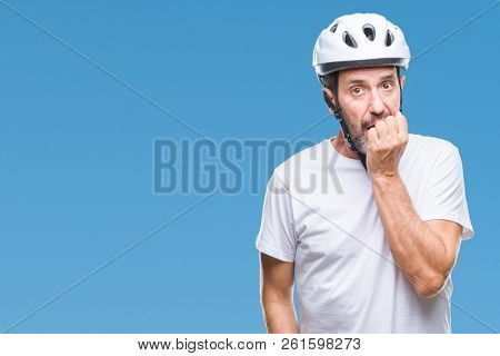 Middle age senior hoary cyclist man wearing bike safety helment isolated background looking stressed and nervous with hands on mouth biting nails. Anxiety problem.