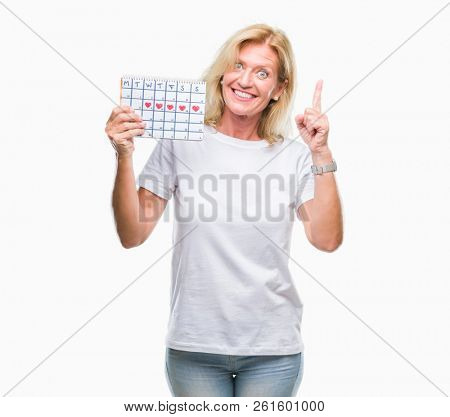 Middle age blonde woman holding menstruation calendar ver isolated background surprised with an idea or question pointing finger with happy face, number one