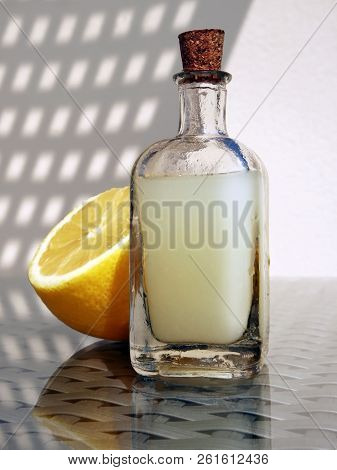 Still Life With Half Of Lemon And Fresh Lemon Juice In The Small Vintage Glass Botlle Against A High