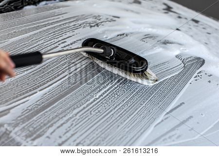 Brush Leaving Strokes In White Shampoo And Foam On Roof Of Silver Car Washed In Self Serve Carwash.