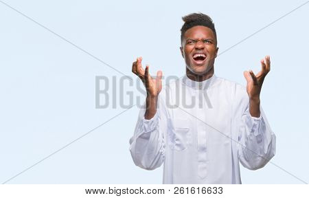 Young arabic african man wearing traditional djellaba over isolated background celebrating mad and crazy for success with arms raised and closed eyes screaming excited. Winner concept