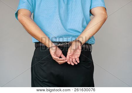 Close-up. Arrested Man Handcuffed Hands At The Back. Isolated On Gray Background. Businessman In Off