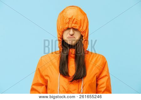 The Young Girl Posing At Studio In Autumn Jacket Isolated On Blue. Human Negative Emotions. Concept 