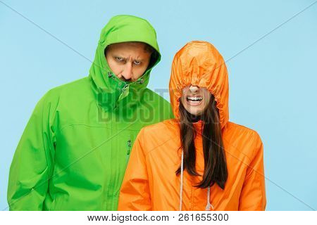The Young Couple Posing At Studio In Autumn Jacket Isolated On Blue. Human Negative Emotions. Concep