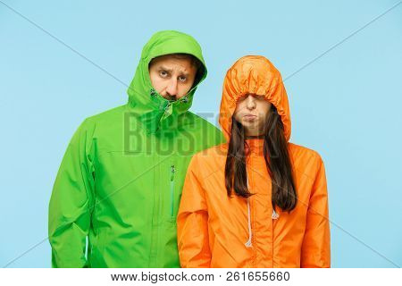 The Young Couple Posing At Studio In Autumn Jacket Isolated On Blue. Human Negative Emotions. Concep