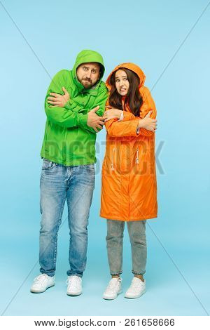 The Young Couple Posing At Studio In Autumn Jacket Isolated On Blue. Human Negative Emotions. Concep