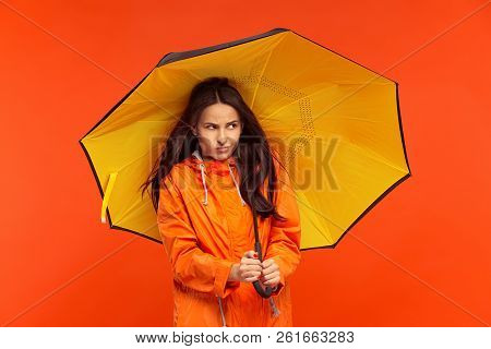 The Young Girl Posing At Studio In Autumn Jacket Isolated On Red. Human Negative Emotions. Concept O