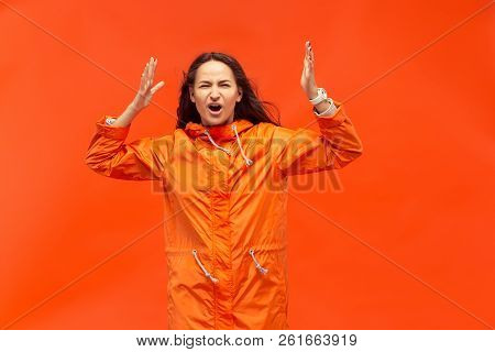 The Young Girl Posing At Studio In Autumn Jacket Isolated On Red. Human Negative Emotions. Concept O