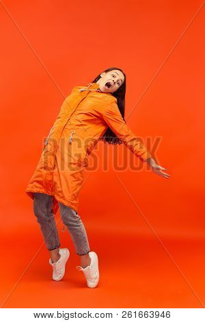 The Young Girl Posing At Studio In Autumn Jacket Isolated On Red. Human Negative Emotions. Concept O