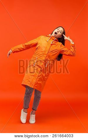 The Young Girl Posing At Studio In Autumn Jacket Isolated On Red. Human Negative Emotions. Concept O