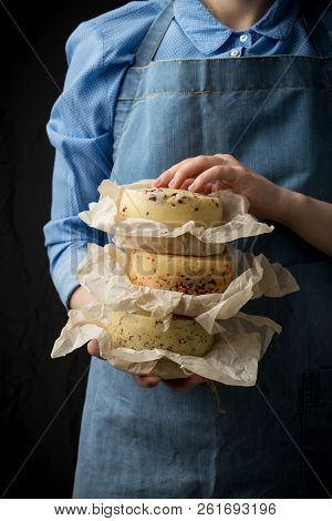 Woman Holding Assorted Cheese Head In Blue Apron On Dark Background