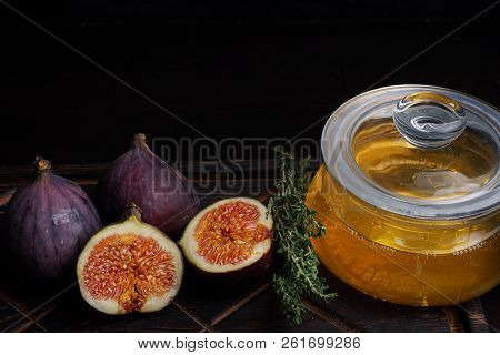 Ripe Figs Lying On A Dark Wooden Board Next To A Sprig Of Thyme For Tea And A Jar Of Linden Honey