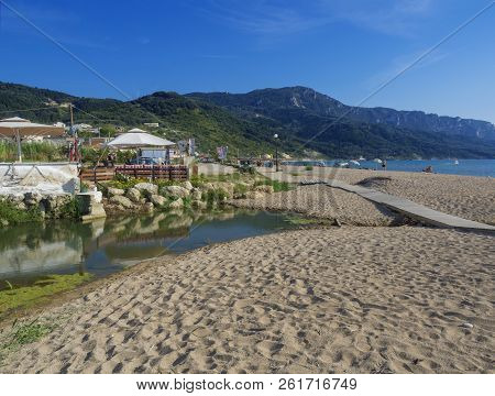 Greece, Corfu, Agios Georgios, September 23, 2018: View On Sea Shore Wooden Promenade With Sand Beac