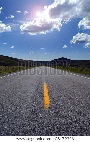 Camino rural con líneas pintadas sol, el cielo y las nubes