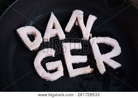 Frying Pan With Word Danger Carved Of Bacon. Unhealthy Food, Overweight, Imbalanced Diet, Reduce Fat