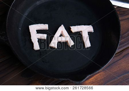 Frying Pan With Word Fat Carved Of Bacon. Unhealthy Food, Overweight, Imbalanced Diet, Reduce Fat, E