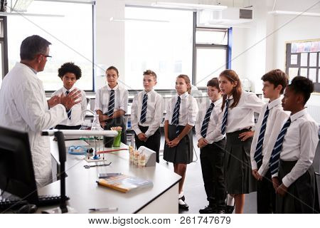 Male High School Tutor Teaching High School Students Wearing Uniforms In Science Class