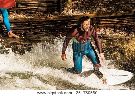 Munich, Germany - Sept 8, 2018: A Man Surfing In The Waves Of The Eisbach River In Downtown Of Munic