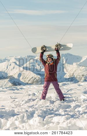 Snowboarder Girl Freerider Is Standing In The Snowy Mountains In Winter Under The Clouds