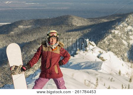 Snowboarder Girl Freerider Is Standing In The Snowy Mountains In Winter Under The Clouds