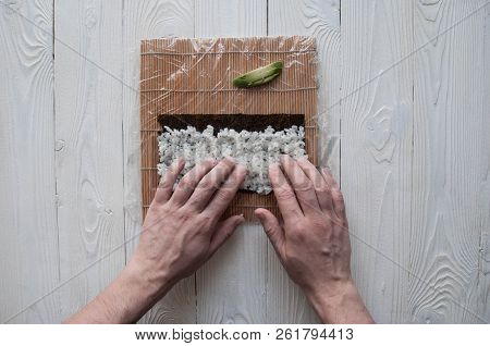 Process of making maki sushi. Cook chef hands preparing rolls with cheese, avocado and sesame seeds 