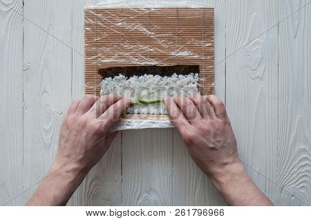 Process of making maki sushi. Cook chef hands preparing rolls with cheese, avocado and sesame seeds 